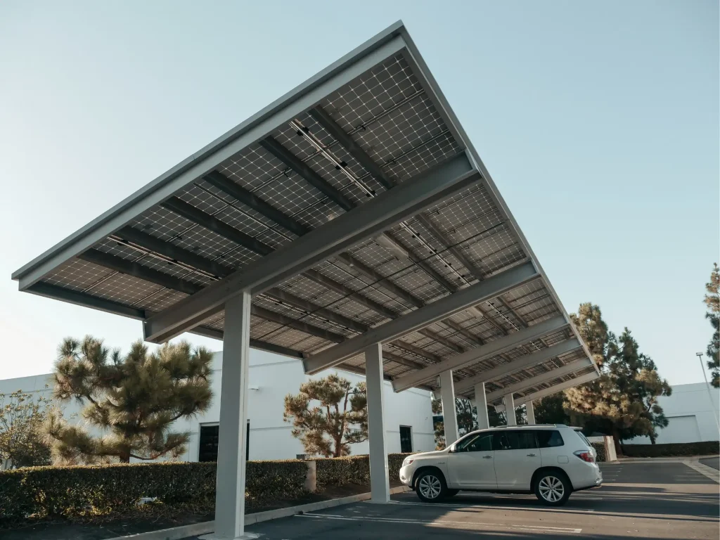 Ein weißes Auto steht unter einem PV-Carport